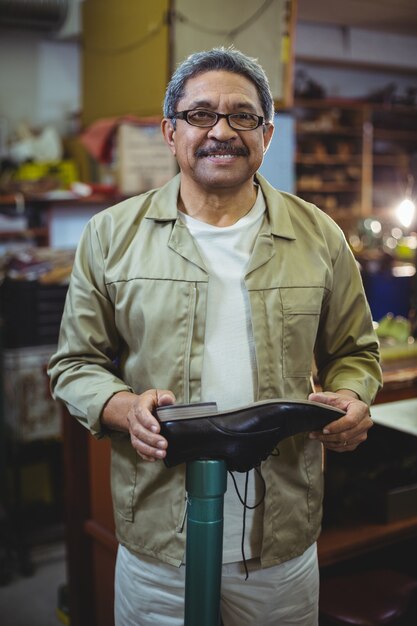 Portrait de cordonnier souriant examinant une chaussure