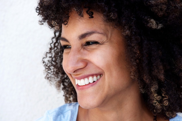 Portrait de côté d&#39;une femme qui rit avec des cheveux bouclés sur fond blanc