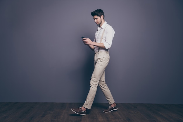 Portrait de côté de profil pleine taille de gars concentré à pied aller copier l'espace utiliser le chat de téléphone intelligent avec ses collègues de travail porter une bonne tenue.