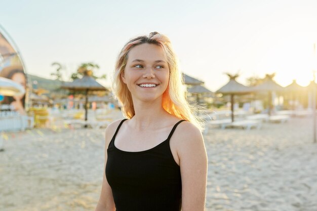 Portrait de coucher de soleil sur la plage d'une adolescente heureuse