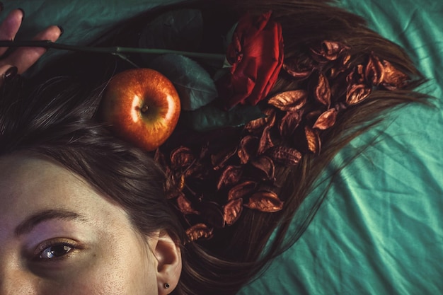 Portrait coupé d'une femme avec une pomme et une rose