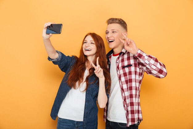 Portrait d'un couple d'adolescents heureux prenant selfie