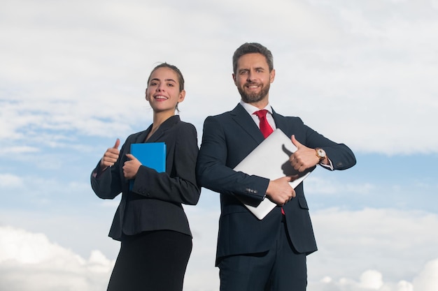 Portrait d'un couple d'affaires en costume avec le pouce levé deux jeunes travailleurs travaillant avec