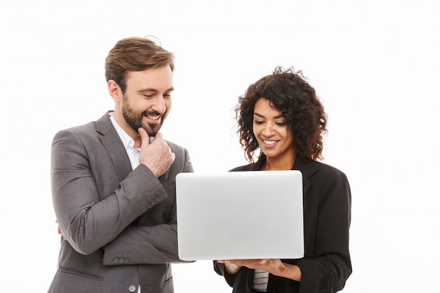 Portrait d'un couple d'affaires souriant à la recherche d'un ordinateur portable