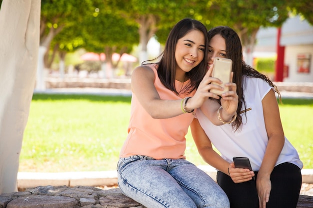 Portrait d'un couple d'amies mignonnes prenant un selfie avec un smartphone à l'école