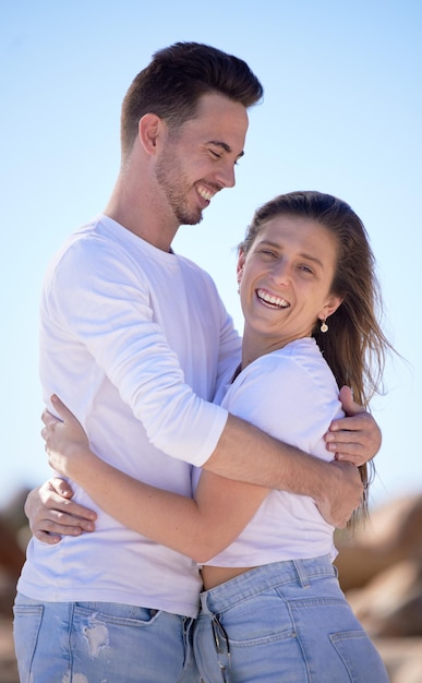 Portrait couple amour et câlin à la plage et heureux avec sourire pour relation rendez-vous romantique ou vacances ensemble Romance homme et femme avec bonheur été et étreinte pour voyage ou vacances