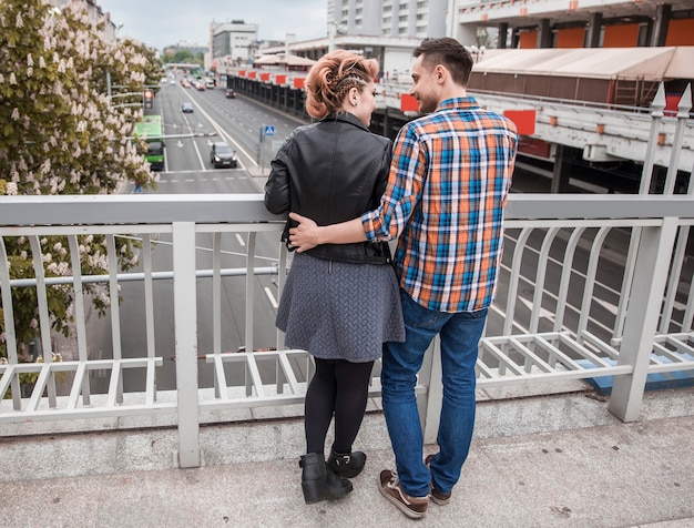 Portrait d'un couple d'amoureux debout sur un pont dans une grande ville