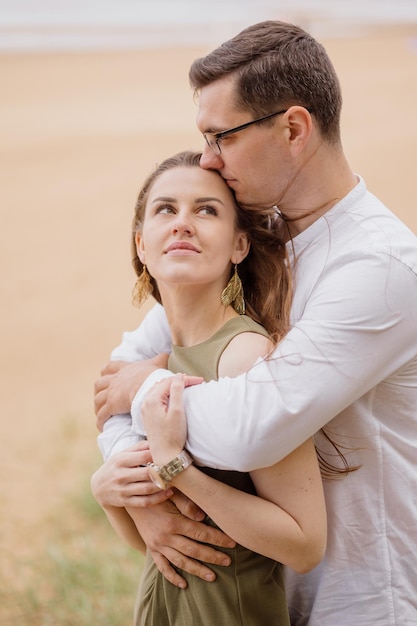 Portrait d'un couple amoureux d'un homme et d'une femme s'embrassant en marchant le long de la plage sur le sable