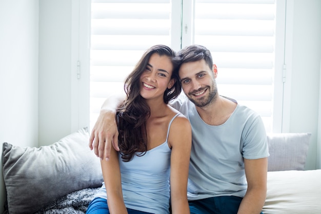 Portrait de couple assis sur le lit dans la chambre à la maison