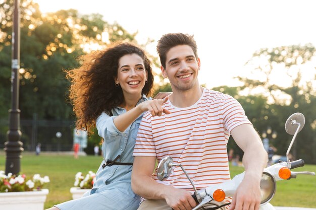 Portrait De Couple Caucasien, Assis Ensemble Sur La Moto Dans Le Parc De La Ville