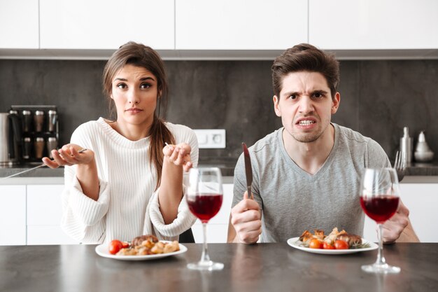 Portrait d'un couple en colère assis à la table de la cuisine