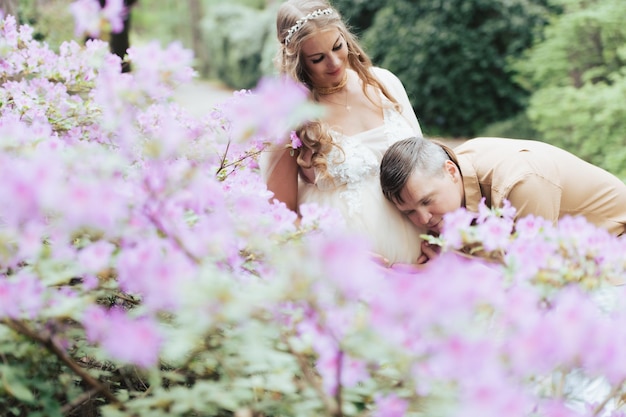 Portrait d'un couple enceinte heureux dans un jardin fleuri Futurs parents dans un parc de rhododendrons en fleurs