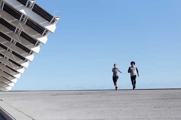 Portrait d'un couple en forme et sportif qui court dans la rue.