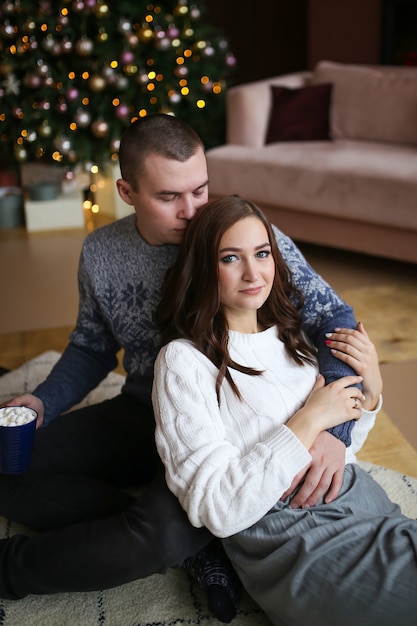 Portrait d'un couple heureux amoureux près d'un arbre de Noël et bokeh dans une maison confortable