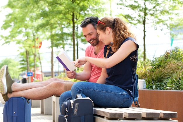 Portrait de couple heureux assis et lisant ensemble à l&#39;extérieur sur un banc