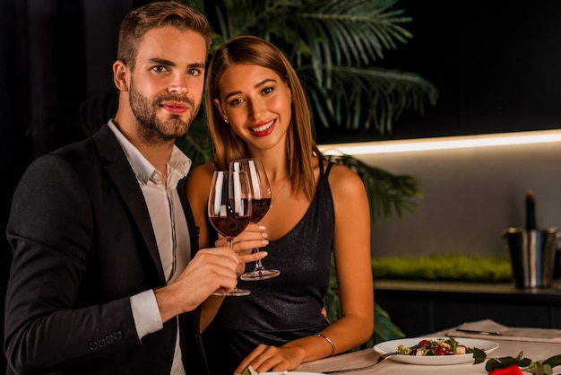 Portrait d'un couple heureux en dîner romantique portant un toast avec du vin et regardant à huis clos