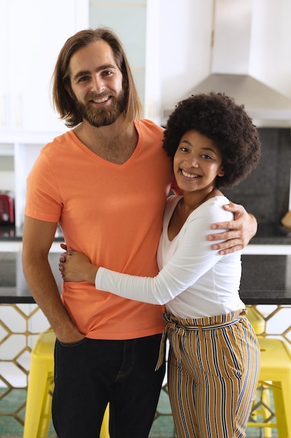 Portrait d'un couple heureux et diversifié dans la cuisine, souriant et embrassant