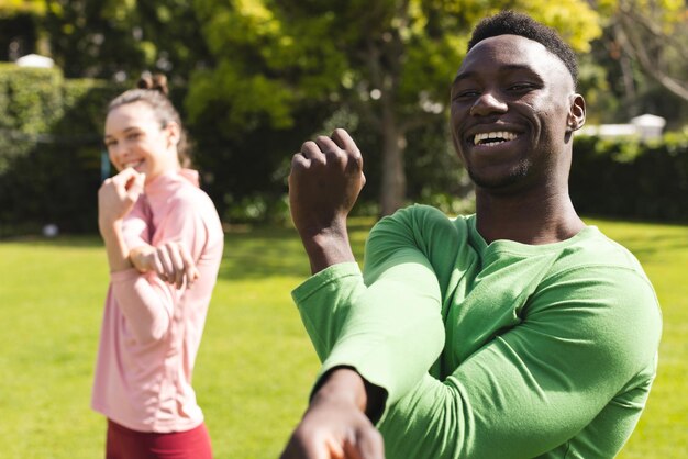 Photo portrait d'un couple heureux et diversifié pratiquant le yoga et s'étirant dans le jardin