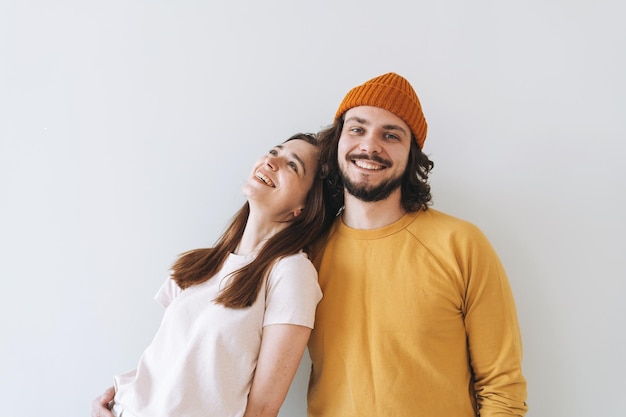 Portrait d'un couple heureux jeune famille riant contre le mur gris