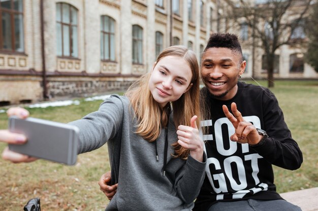 Portrait d'un couple heureux de jeunes adolescents prenant un selfie à l'extérieur sur le campus de la ville