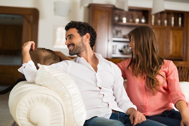 Portrait d&#39;un couple heureux jouant avec leur chat sur le canapé.