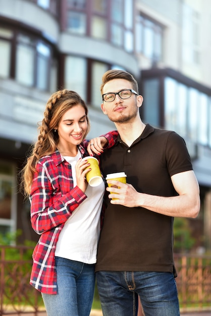 Portrait d'un couple heureux marchant dans la rue avec du café