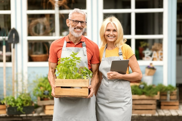 Portrait d'un couple heureux et mature de propriétaires de serres posant ensemble à l'extérieur