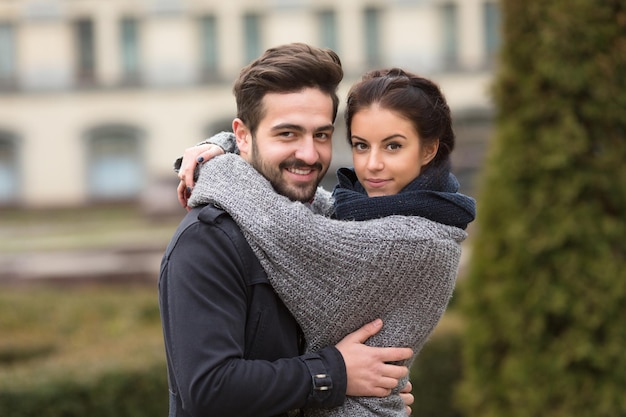 Portrait d'un couple heureux s'embrassant dans le parc en automne et regardant la caméra.