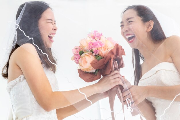 Portrait de couple homosexuel asiatique tenant une fleur en robe de mariée. Concept LGBT lesbienne.