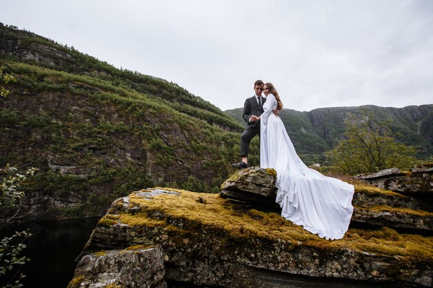 Portrait d'un couple de mariage debout sur un rocher. Les nouveaux mariés se blottissent les uns contre les autres