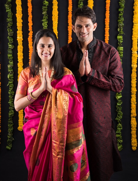 Portrait de couple marié indien en tenue traditionnelle à Namaskara ou prière ou pose de bienvenue ou tenue de puja thali