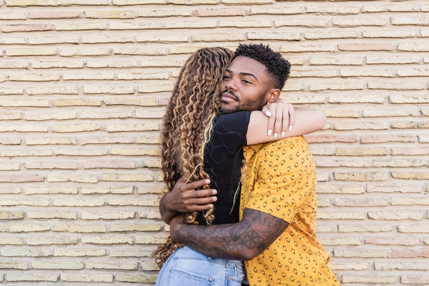 Portrait d'un couple multiracial heureux amoureux étreignant dans un fond de brique