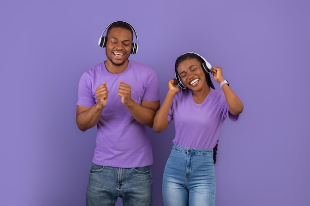 Portrait d'un couple noir émotionnel dans des écouteurs dansant au studio