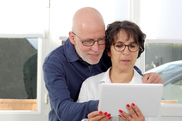 Portrait d'un couple de personnes âgées heureux à l'aide de tablette numérique