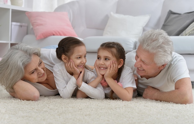 Portrait d'un couple de personnes âgées heureux avec petits-enfants à la maison