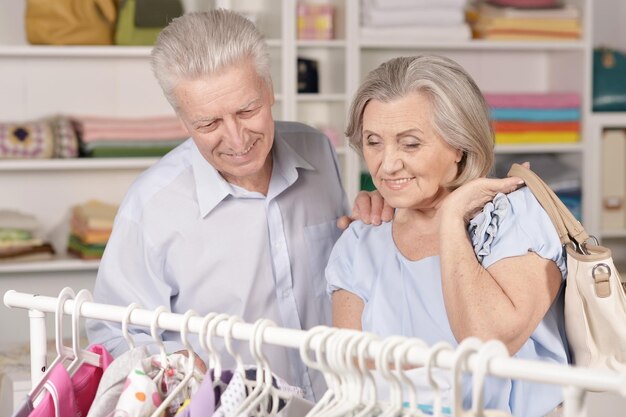 Portrait d'un couple de personnes âgées heureux près d'un rack avec des chemises