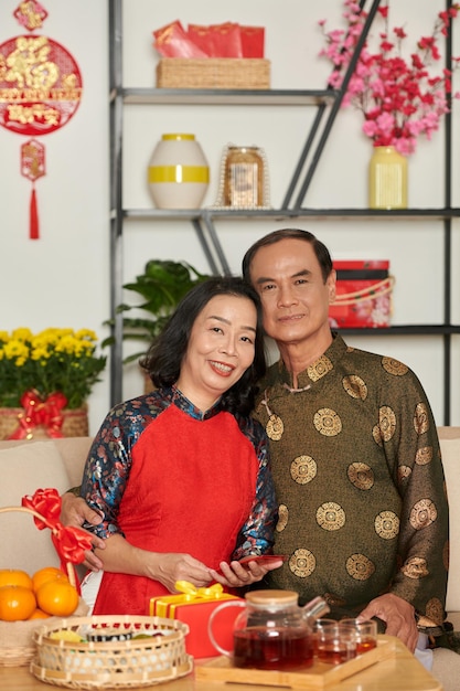 Portrait d'un couple de personnes âgées joyeux décorant la maison et préparant tout pour la célébration du tet familial