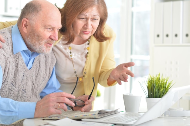 Portrait d'un couple de personnes âgées avec un ordinateur portable