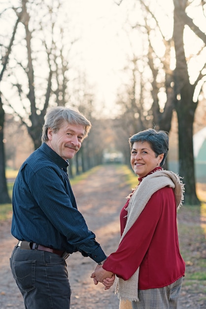 Portrait de couple de personnes âgées romantique marchant en plein air mains ensemble dans le parc.