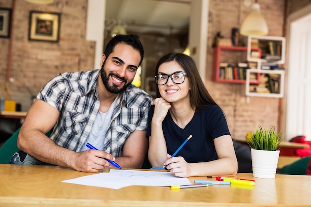 Portrait d'un couple de pigistes barbu et fille brune travaillant avec un ordinateur portable dans un concept de réussite de travail d'équipe de bureau de coworking moderne et élégant