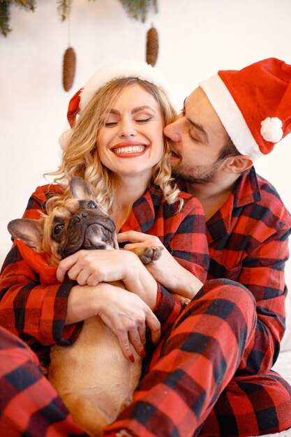 Portrait d'un couple portant un pyjama rouge à carreaux de Noël avec un chien