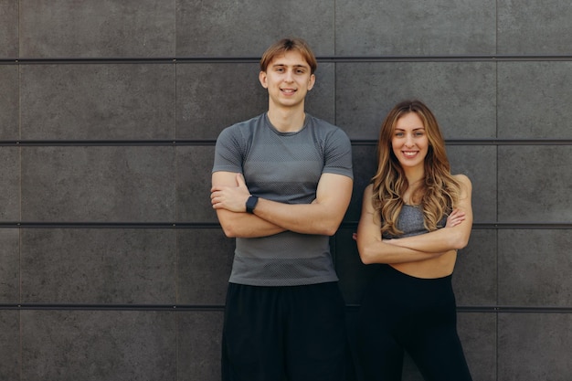 Portrait d'un couple de remise en forme souriant et regardant loin Homme mûr gai et belle femme riant tout en se reposant après avoir couru Couple en bonne santé appuyé contre le mur avec espace de copie