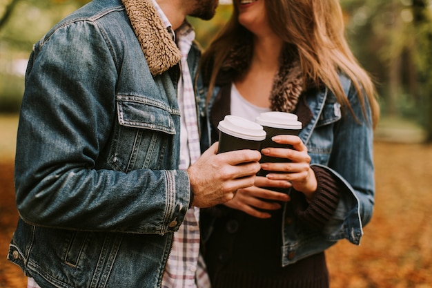 Portrait de couple romantique avec café marchant en plein air dans le parc en automne