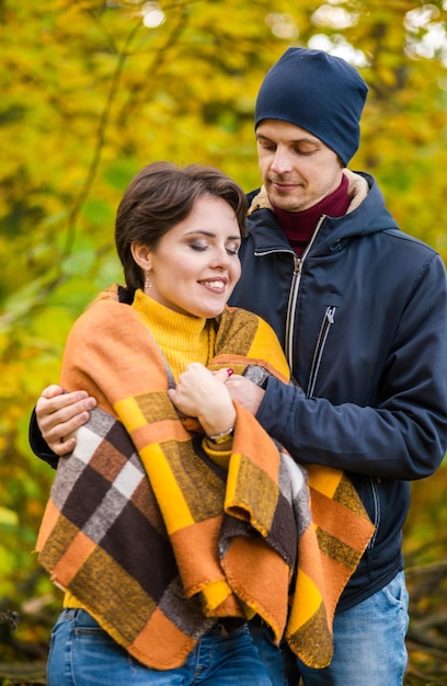 Portrait d'un couple romantique dans le parc de la ville d'automne homme et femme posant parmi les feuilles jaunes femme sont