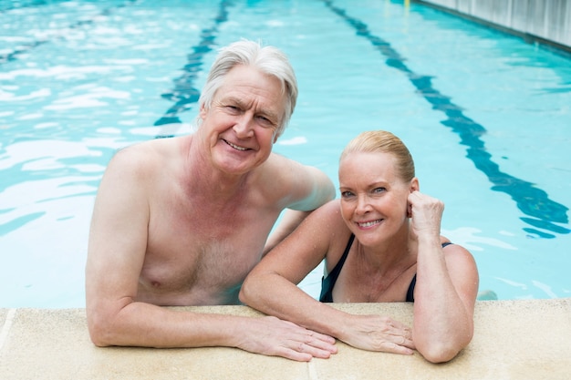 Portrait de couple se penchant au bord de la piscine