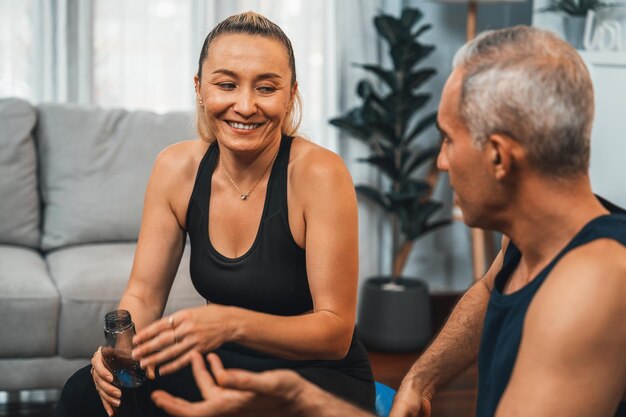 Photo portrait de couple senior athlétique et sportif en vêtements de sport assis sur le canapé en tant que concept d'exercice à domicile style de vie corporel en bonne santé après la retraite clout