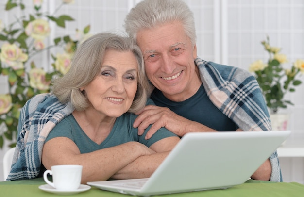 Portrait de couple senior avec ordinateur portable à la maison