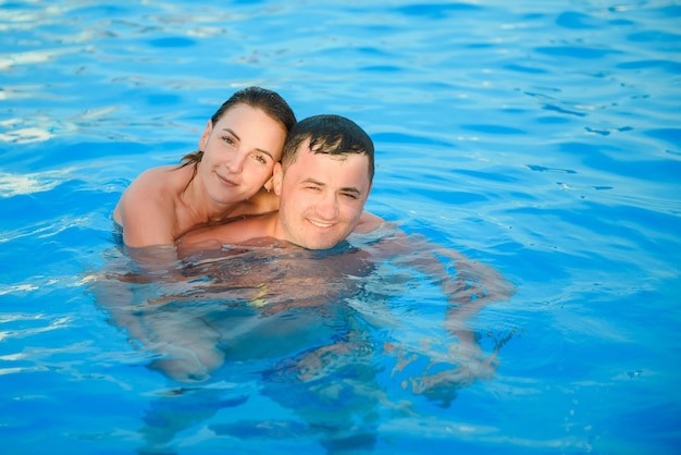 Portrait d'un couple souriant dans une piscine