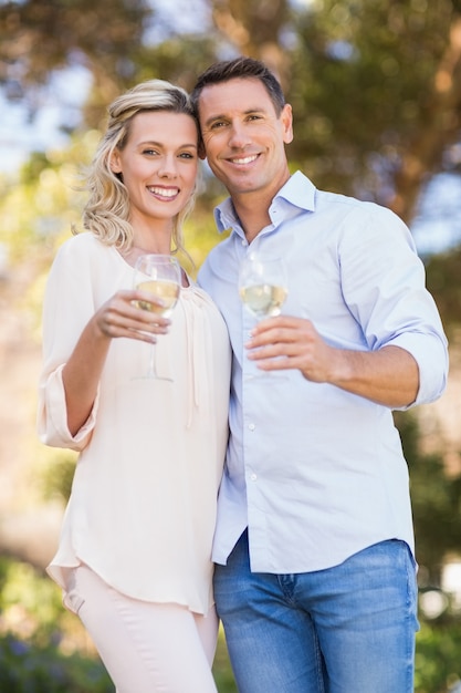 Portrait de couple souriant embrassant et tenant le verre à vin