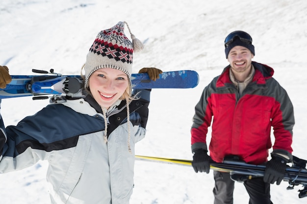 Portrait d&#39;un couple souriant avec des planches de ski sur la neige